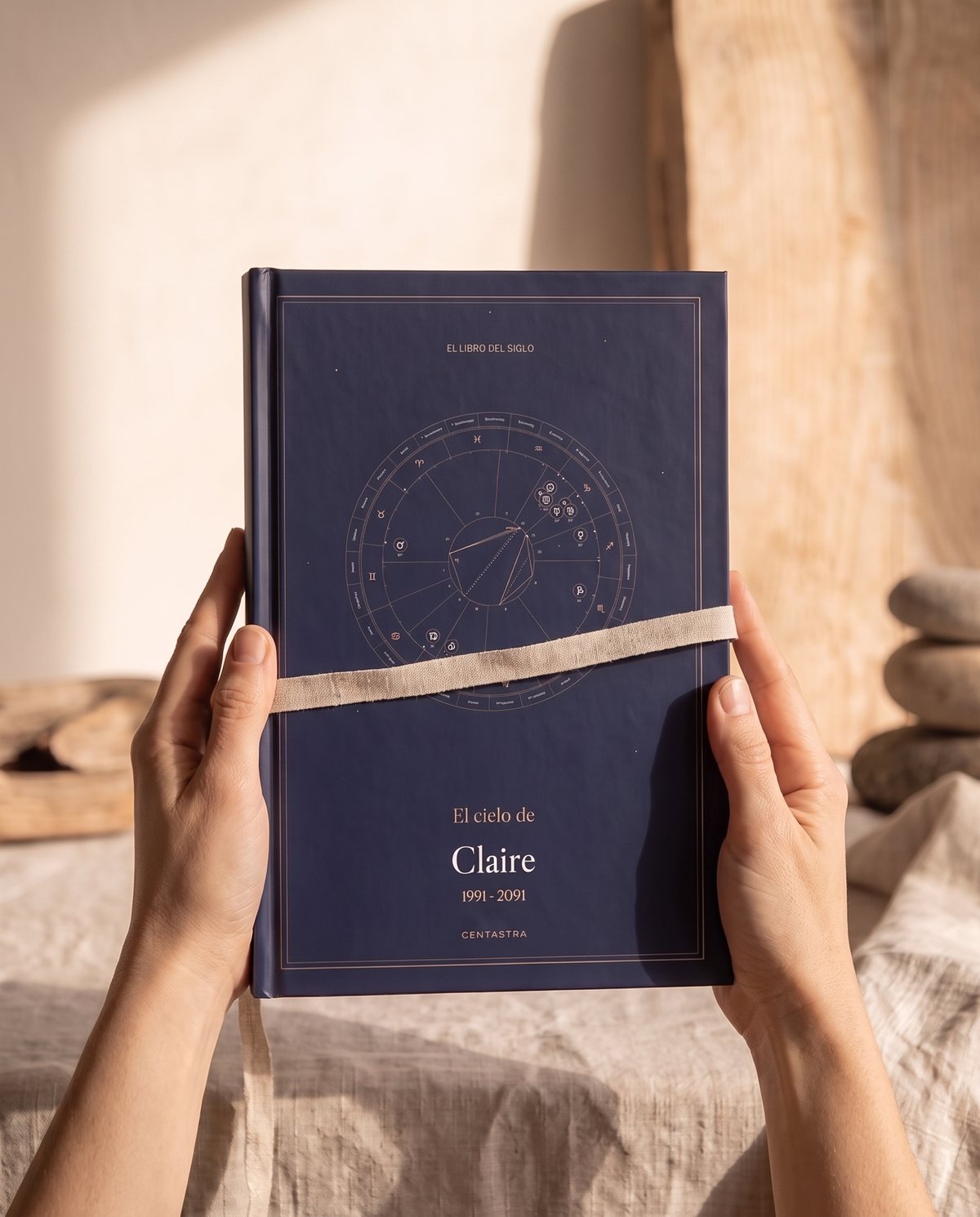 El libro de Centastra, cubierta azul noche con su carta celeste, atado con una cinta, sobre lino